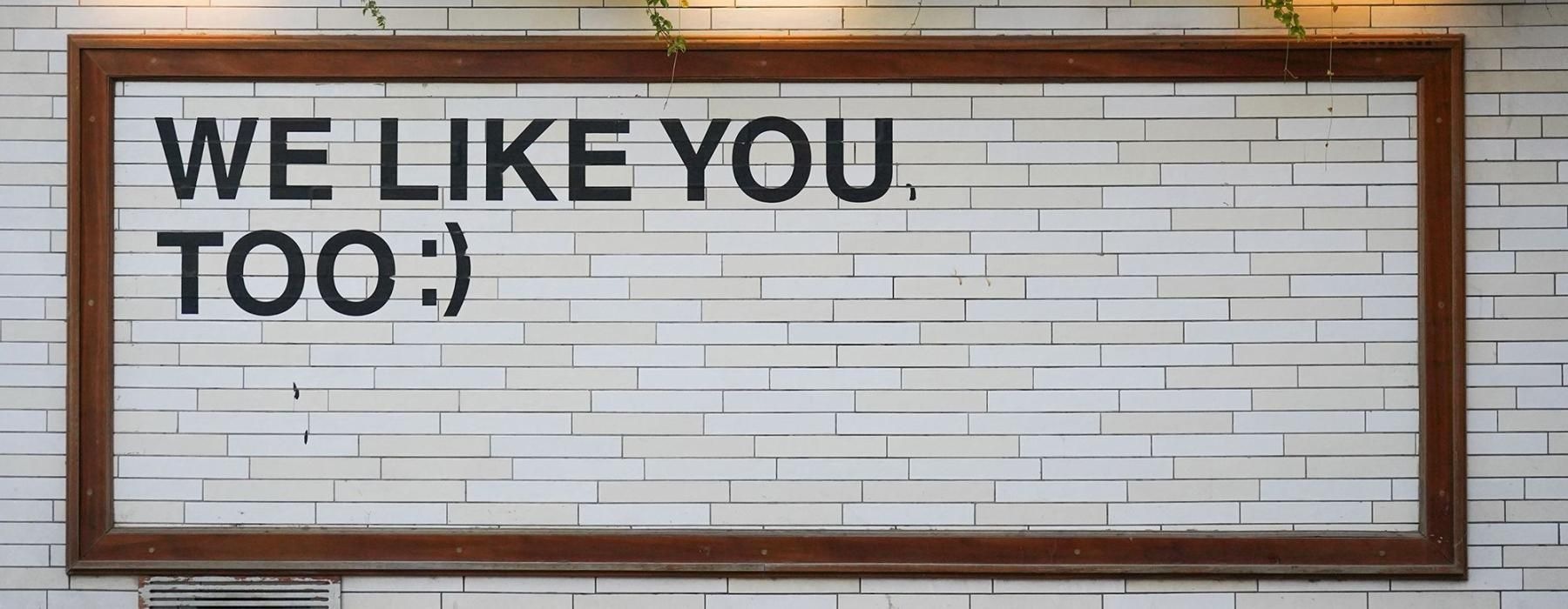a sign on a tile wall that says, "We like you too"